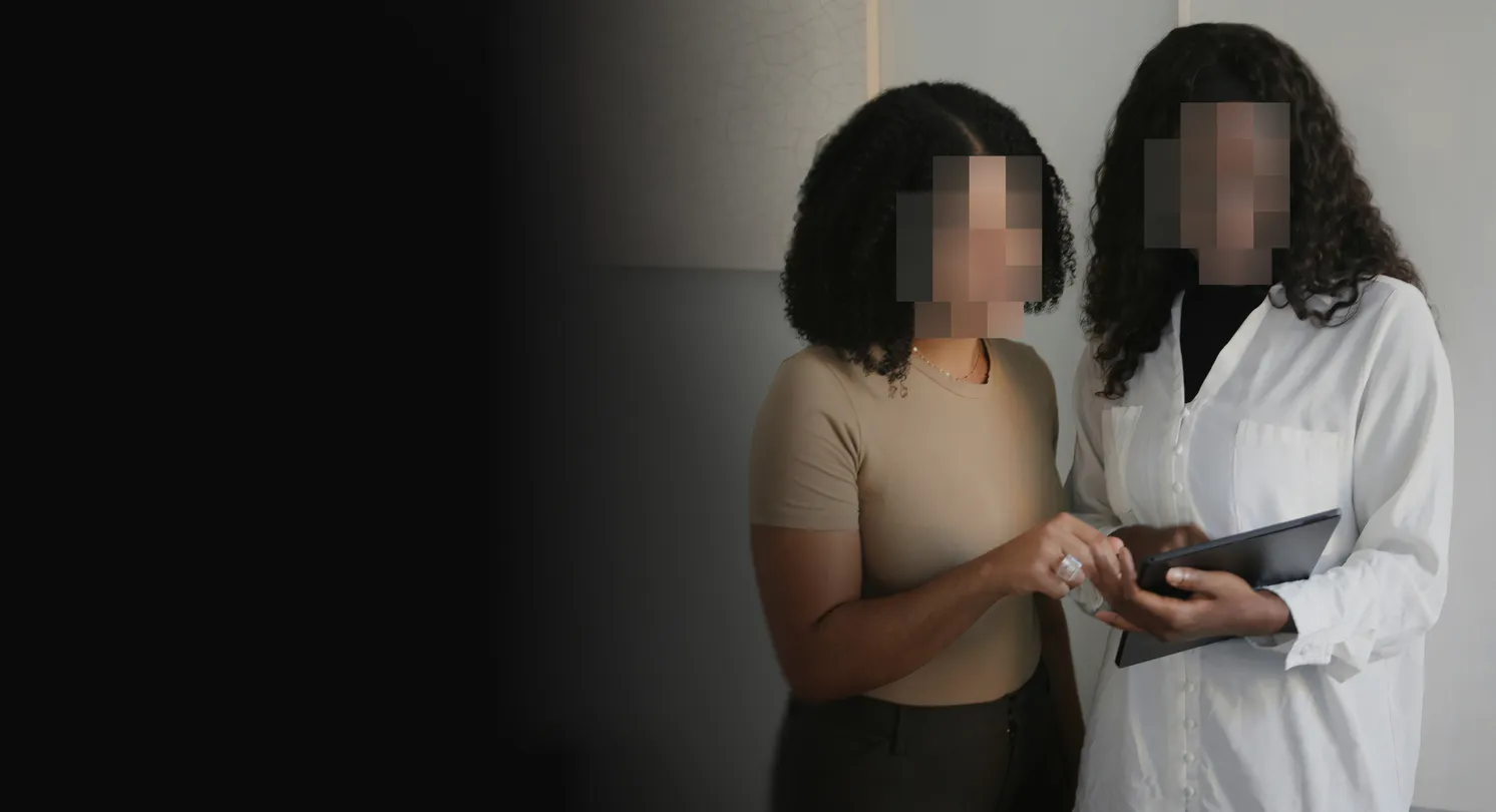Two women with blurred faces, symbolizing identity protection, are using a tablet to check their cyberattack coverage details.