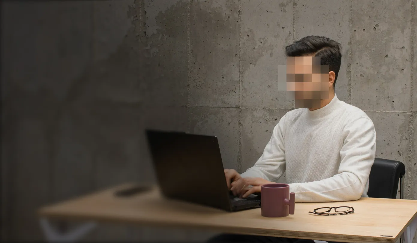 A man with a blurred face using a laptop to see what NordProtect’s cyberattack coverage includes.