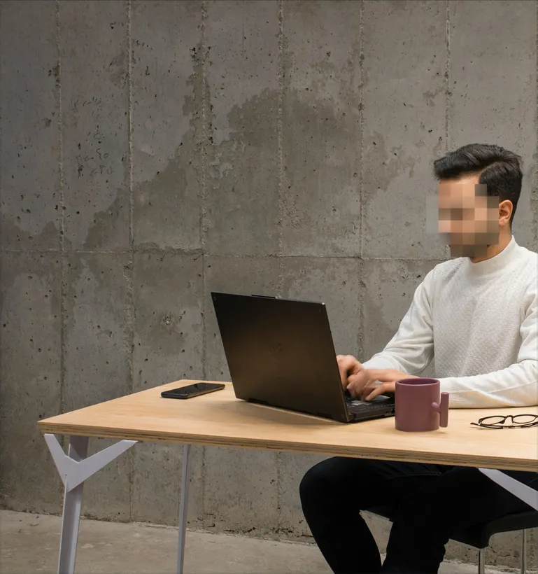A man with a blurred face using a laptop to see what NordProtect cyberattack coverage includes.