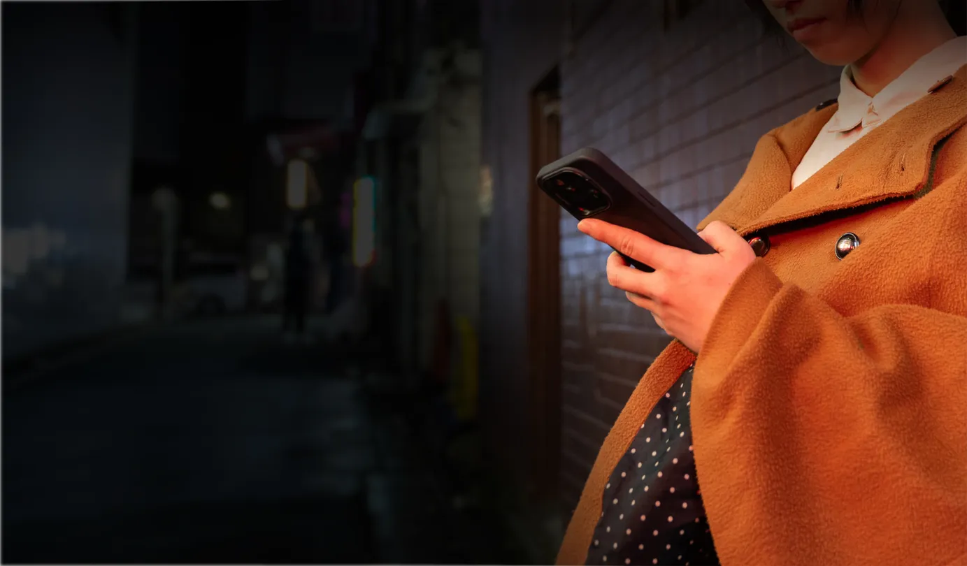 A woman holding a smartphone, checking for malware breach alerts from NordProtect.